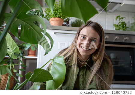 Portrait happy woman plant lover smiling taking care about houseplant monstera on kitchen at home. Portrait happy woman plant lover smiling taking care about houseplant monstera on kitchen at home. 119040783