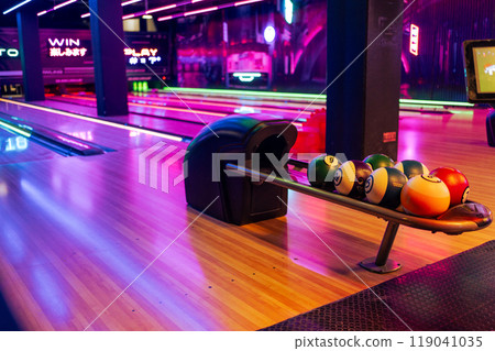 Various bowling balls in stand with wooden lane at 119041035