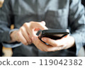 A person operating a black smartphone with their index finger 119042382
