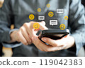 Emojis with various facial expressions, such as smiling faces, and speech bubbles for messages are floating above the smartphone. 119042383