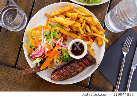 Juicy roasted duck magret served sauce framboise, french fries and vegetables 119044896