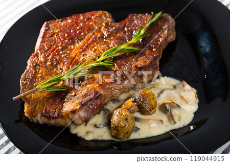 Beef steak with mushrooms sauce branch of rosemary at black plate 119044915