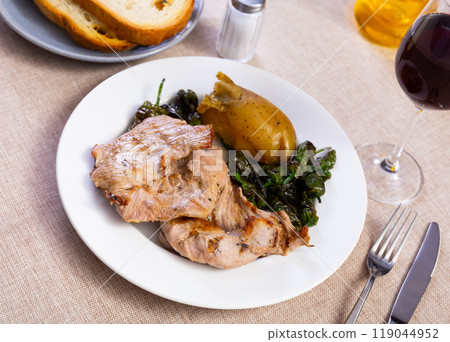 Fried pork tenderloin, garnished with potatoes baked in peel and pieces of bell pepper Fried pork tenderloin, garnished with potatoes baked in peel and pieces of bell pepper 119044952