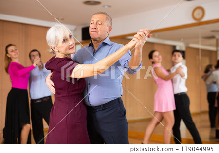 Ederly couple enjoying slow foxtrot in dance studio Ederly couple enjoying slow foxtrot in dance studio 119044995