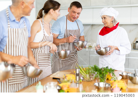 Amiable senior female chef running group culinary courses Amiable senior female chef running group culinary courses 119045003