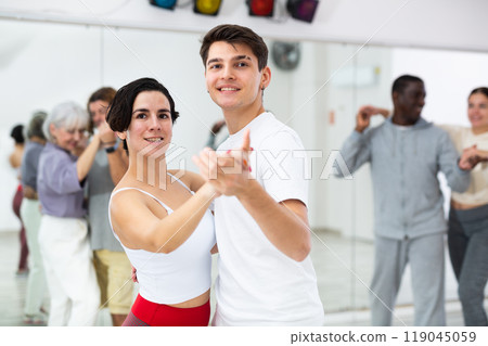 Latina and young guy dancing slow foxtrot as couple 119045059