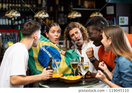 Emotional diverse sport fans with flag of Brazil, rejoicing with of beer in the pub 119045110