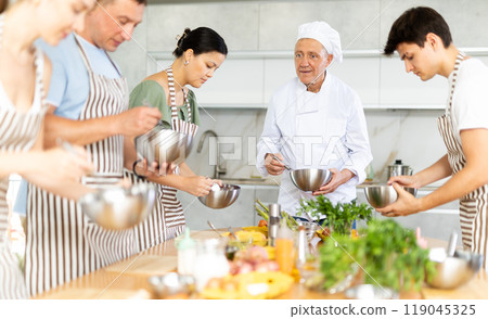 Elderly man teaching cooking to group of people 119045325