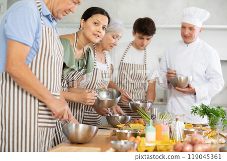 Pleased middle-aged woman attendee of cooking course learning how to mix sauce 119045361