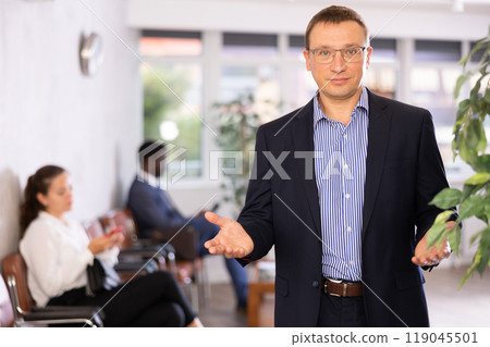 Dispassionate secretary man stands at reception with folder and list of guests and expects visitors 119045501