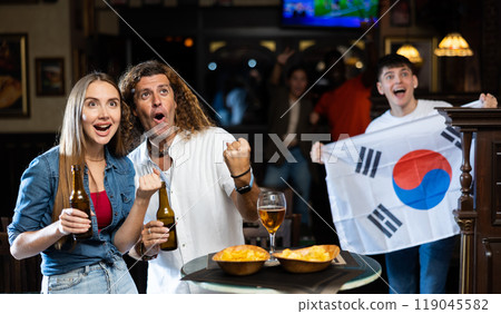 Group of happy friends with flag of South Korea celebrating victory of their favorite team in beer bar 119045582