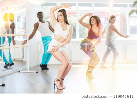 Girl in high heels sitting and lying on floor performing erotic dances during rehearsal with friends 119045611