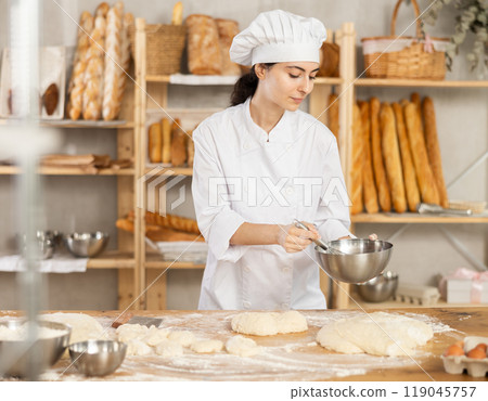 Baker girl in white uniform and chefs hat with bowl and whisk in her hands Baker girl in white uniform and chefs hat with bowl and whisk in her hands 119045757