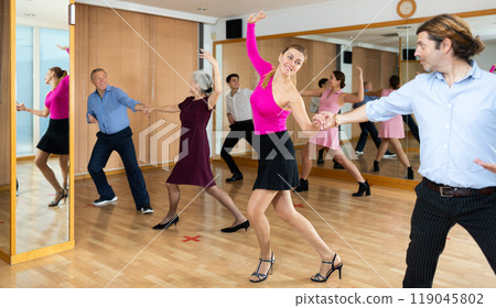 Middle-aged pair practicing ballroom dance in dance studio Middle-aged pair practicing ballroom dance in dance studio 119045802