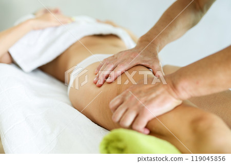 Hands of old masseur conducting hip massage for woman client Hands of old masseur conducting hip massage for woman client 119045856