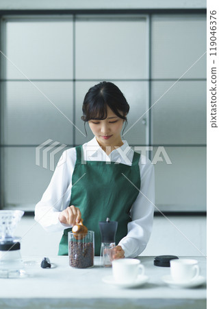 週末早上,一位年輕的女店員正在煮咖啡 週末早上,一位年輕的女店員正在煮咖啡 119046376