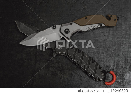 Two opened tactical military knives with sharp blade. Tool on dark concrete background. Two opened tactical military knives with sharp blade. Tool on dark concrete background. 119046803