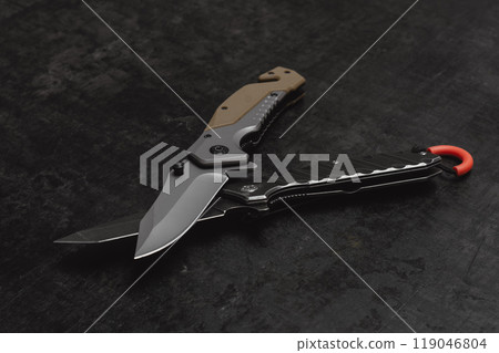 Two opened tactical military knives with sharp blade. Tool on dark concrete background. Two opened tactical military knives with sharp blade. Tool on dark concrete background. 119046804