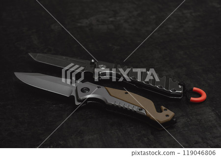 Two opened tactical military knives with sharp blade. Tool on dark concrete background. Two opened tactical military knives with sharp blade. Tool on dark concrete background. 119046806