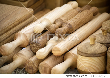 Wooden rolling pins arranged in a row on a rustic wooden table under natural light 119047326