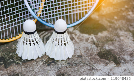 White badminton shuttlecocks and badminton rackets on dark background to enhance doing exercise. White badminton shuttlecocks and badminton rackets on dark background to enhance doing exercise. 119048425
