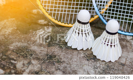 White badminton shuttlecocks and badminton rackets on dark background to enhance doing exercise. 119048426