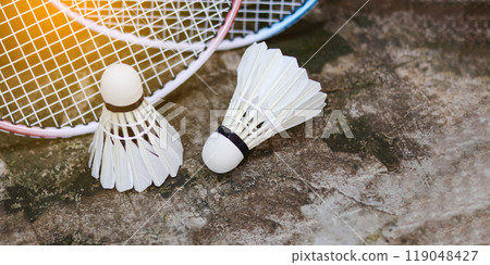 White badminton shuttlecocks and badminton rackets on dark background to enhance doing exercise. 119048427