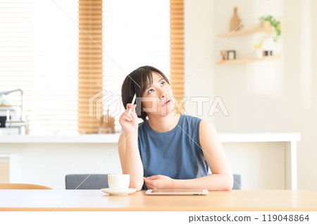 A woman thinking with a touch pen in her hand A woman thinking with a touch pen in her hand 119048864