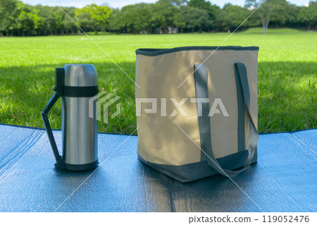 有草地的公園裡放置休閒床單、水瓶和冰袋。 119052476
