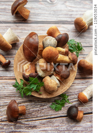 Assorted fresh mushrooms and herbs arranged on a wooden board in a rustic kitchen setting 119053034