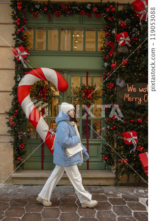woman walking by city street decorated for christmas 119053088
