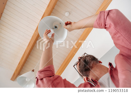 Man changing LED bulbs at home. Concept of energy efficiency, longevitiy and environmental impact of electronic bulb. 119053318