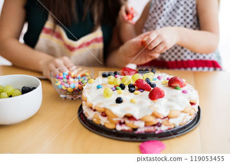 Mom and daughter preparing birthday party, making, decorating birthday cake. 119053455