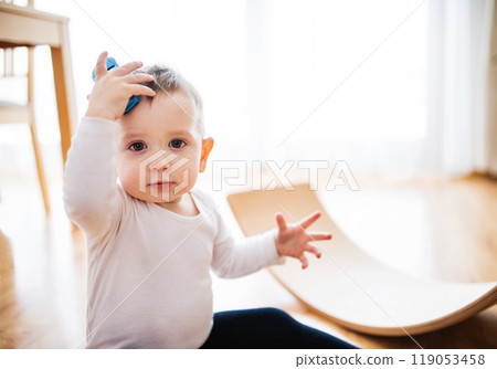 Toddler boy is playing with toy car in living room. 119053458