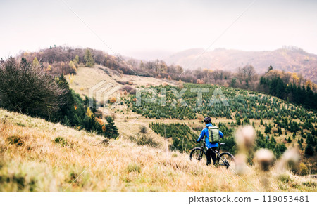 Cyclist far in the middle of beautiful nature riding down the hill. Concept of healthy lifestyle. 119053481