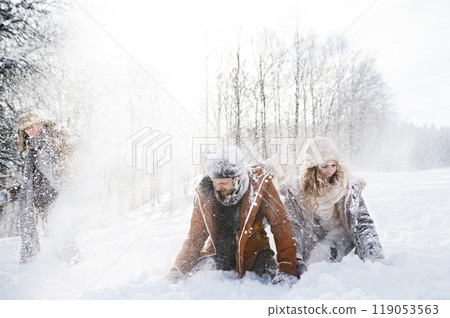 Friends in snowball fight in snowy nature, throwing snow and having fun. First snowfall of the season. Friends in snowball fight in snowy nature, throwing snow and having fun. First snowfall of the season. 119053563