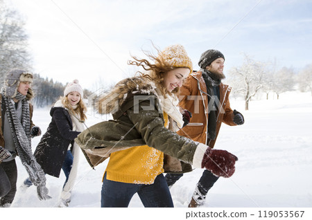 Friends in snowball fight, running and catching each other in snowy nature. First snowfall of the season. 119053567