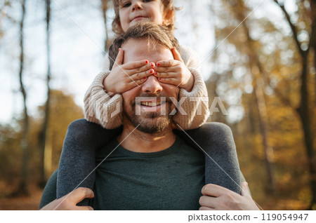 Father walking with daughter on his shoulders across autumn forest. Dad and girl having fun outdoors. Father walking with daughter on his shoulders across autumn forest. Dad and girl having fun outdoors. 119054947