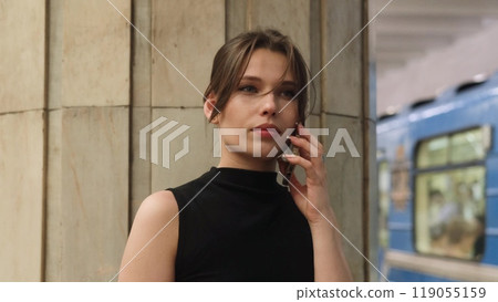 A beautiful brunette talks on the phone while waiting for her train at the metro station. 119055159