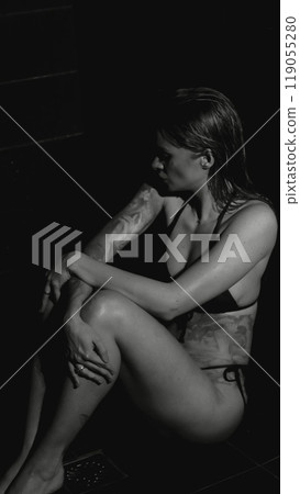 Sexy woman fashion model takes a shower in a swimsuit, posing for the camera. Monochrome photography. 119055280
