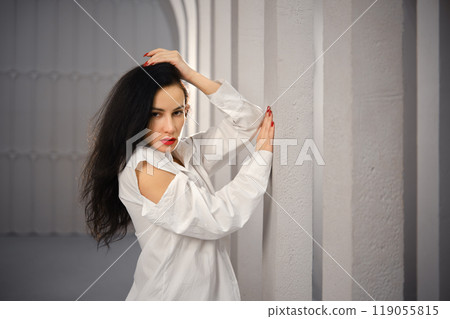Strict woman rested her elbow against the column 119055815