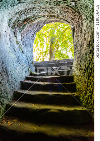 Visitors navigate the ancient stone steps leading out of Frydstejn Castle ruins in Bohemian Paradise, surrounded by lush greenery and historical architecture. Visitors navigate the ancient stone steps leading out of Frydstejn Castle ruins in Bohemian Paradise, surrounded by lush greenery and historical architecture. 119056418