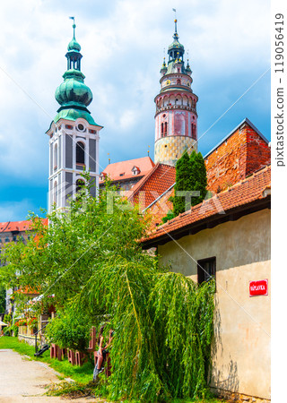 The iconic towers of Cesky Krumlov Castle rise prominently against a backdrop of blue skies, showcasing the stunning architectural details in the heart of Czechia. 119056419