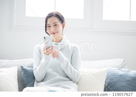 Close-up of a woman tapping on her smartphone, winter ice blue Close-up of a woman tapping on her smartphone, winter ice blue 119057627