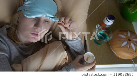 A woman cannot fall asleep and wants to drink a capsule with melatonin, a sleeping pill. Manifestations of jitlag or insomnia. Regulation of biological rhythms 119058695