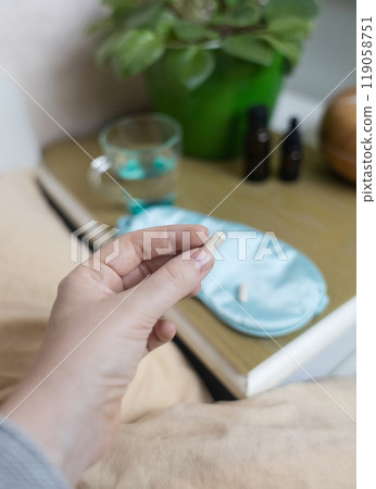 A woman cannot fall asleep and wants to drink a capsule with melatonin, a sleeping pill. Manifestations of jitlag or insomnia. Regulation of biological rhythms 119058751