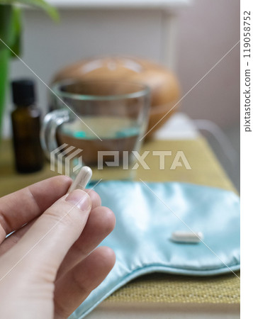 A woman cannot fall asleep and wants to drink a capsule with melatonin, a sleeping pill. Manifestations of jitlag or insomnia. Regulation of biological rhythms 119058752