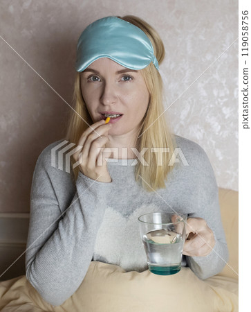 A woman cannot fall asleep and wants to drink a capsule with melatonin, a sleeping pill. Manifestations of jitlag or insomnia. Regulation of biological rhythms A woman cannot fall asleep and wants to drink a capsule with melatonin, a sleeping pill. Manifestations of jitlag or insomnia. Regulation of biological rhythms 119058756