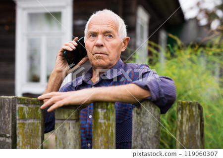 Portrait of an male farmer on backyard country house using smartphone phone for communication Portrait of an male farmer on backyard country house using smartphone phone for communication 119060307