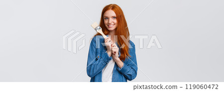 Creative pretty redhead female in denim shirt, creating new art, painting, making repair works in own room, holding paintbrush and smiling tempting, standing white background 119060472